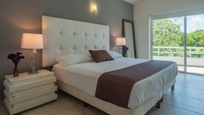 A neatly made bed with a tufted headboard, two bedside lamps, and a view of greenery through a large window. - Spacious villa with 5 bedrooms and WiFi, AC in charming Caribbean community (SOLIDARIDAD)