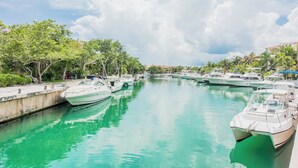 A marina with several boats docked along a calm waterway, surrounded by lush greenery and buildings in the background. - Spacious villa with 5 bedrooms and WiFi, AC in charming Caribbean community (SOLIDARIDAD)