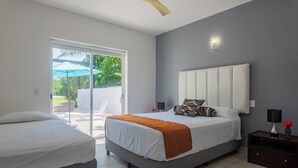 A bedroom with a bed, a nightstand, a ceiling fan, and a view of the outdoors. - Spacious villa with 5 bedrooms and WiFi, AC in charming Caribbean community (SOLIDARIDAD)