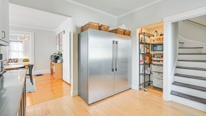 Una cocina moderna con refrigerador de acero inoxidable, piso de madera y una despensa empotrada.