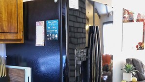 Una cocina con un refrigerador negro, gabinetes de madera y un dispensador de agua integrado.