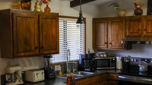 Una cocina con armarios de madera, una isla central con taburetes de bar, un microondas y un tostador.
