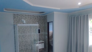 Ein Badezimmer mit einer Duschkabine, einem Waschbecken und einer Tür zu einem weiteren Raum.