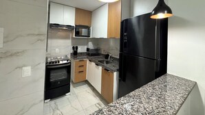 Eine moderne Küche mit einem schwarzen Kühlschrank, Granit Arbeitsplatten und einer Mikrowelle.