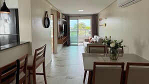Eine moderne Küche mit Backofen, ein Essbereich mit Marmorboden und ein Wohnbereich mit Sofa und Fernseher.