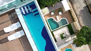 Ein Luftbild eines Schwimmbeckens mit zwei Liegestühlen, einer kleinen Whirlpoolanlage und einer Terrassenanlage mit Tisch und Stühlen.