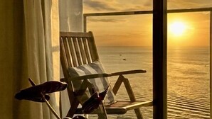 A balcony with a wooden chair and a cushion, overlooking a body of water during sunset. - Seaview Bliss Studio By Tropical Elegance (Kota Kinabalu)