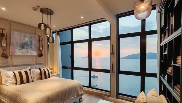 A bedroom with a large bed, a view of the sea, and a bookshelf. - Seaview Bliss Studio By Tropical Elegance (Kota Kinabalu)