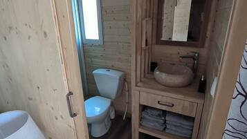 Et badeværelse i en træhytte med toilet, vask og spejl.