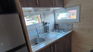 A compact kitchen with wooden cabinets, a stainless steel sink, and a window overlooking the outside.