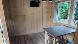 A compact kitchen with wooden walls, a dark countertop, and a window with a view of greenery.