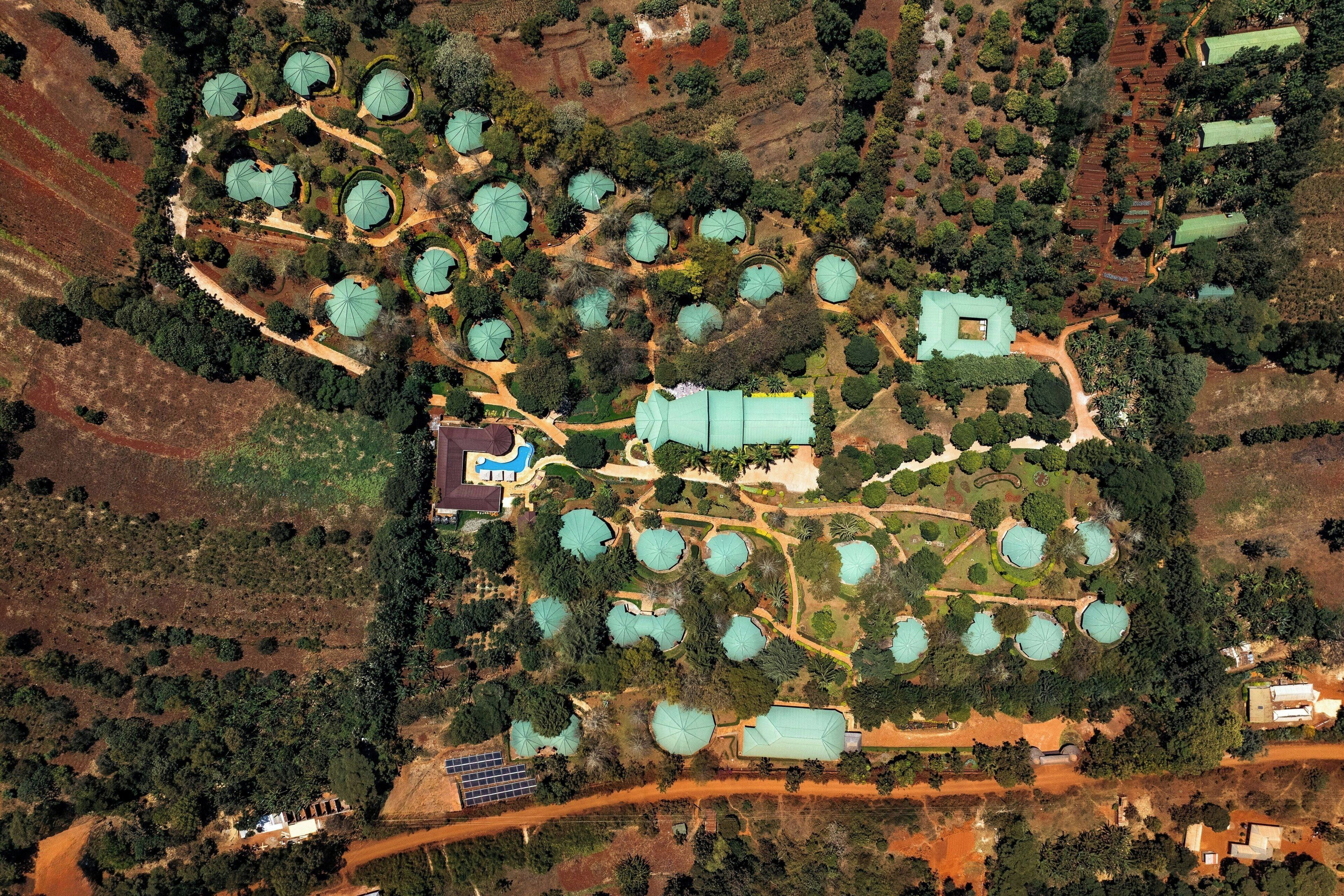 Vista aérea de un complejo turístico con varias edificaciones en forma de cúpula, rodeado de jardines ajardinados y senderos.