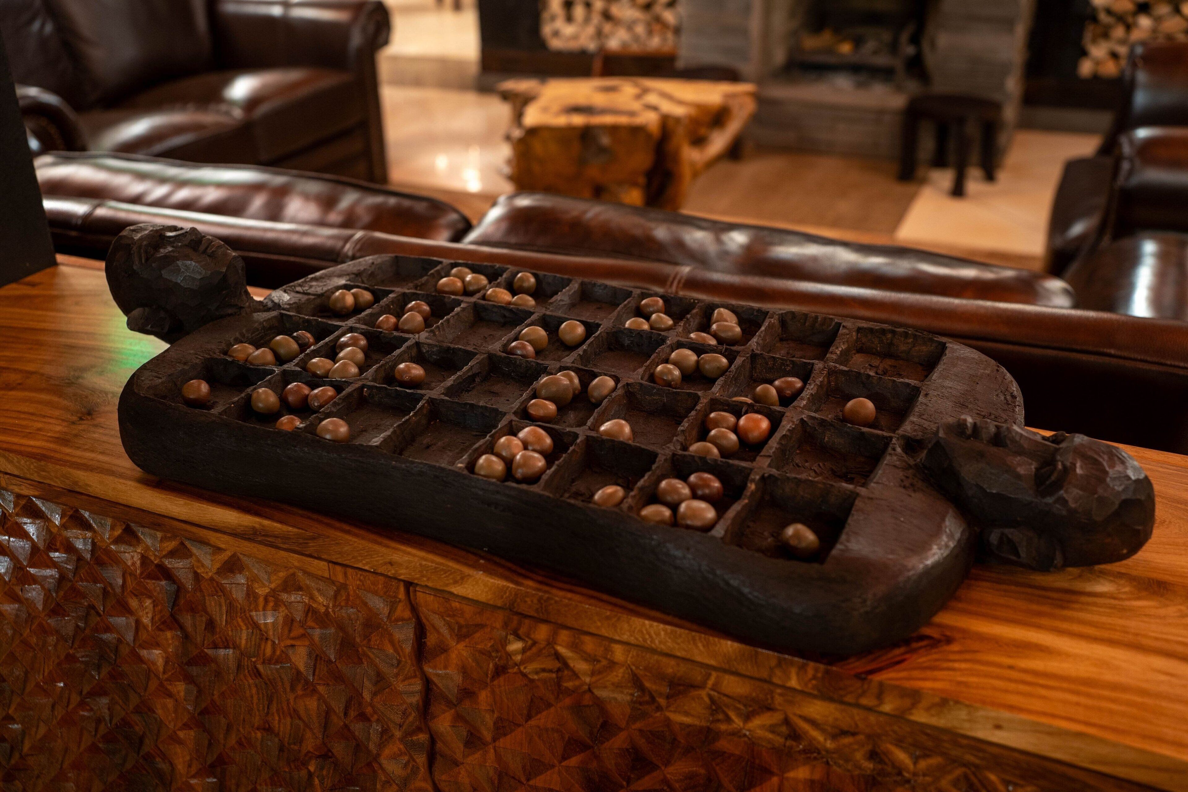 A wooden board game with nuts, placed on a wooden surface in a room with leather furniture.