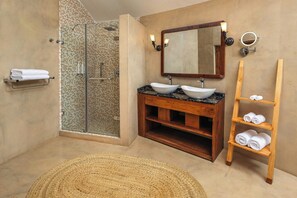 A bathroom with a glass-enclosed shower, a wooden vanity with a vessel sink, and a wooden shelf with towels. - Turaco Ngorongoro Valley, a Tribute Portfolio Lodge (Karatu)