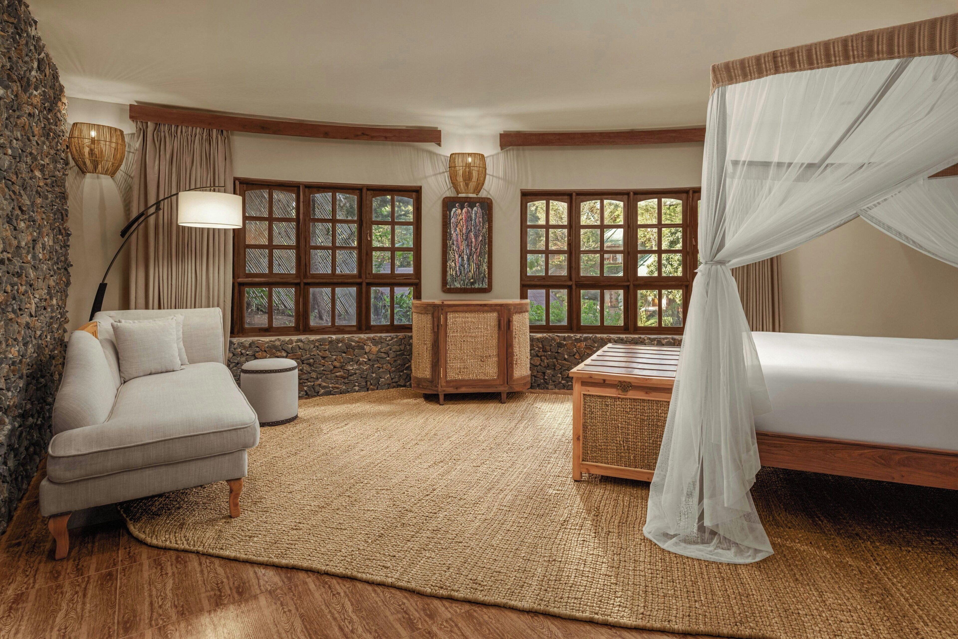 A room with a bed, a sofa, a table, and a lamp.