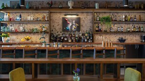 Eine Bar mit mehreren Flaschenregalen, einem zentralen Gemälde und einem runden Tisch mit Stühlen.
