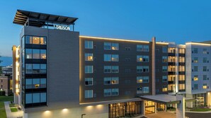 Ein modernes Hotel mit mehreren Etagen, einem überdachten Eingang und gut beleuchteten Fenstern.