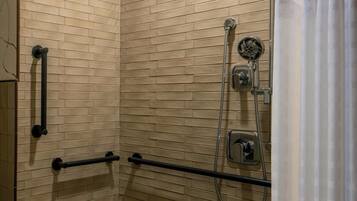 A shower area with a tiled floor, a showerhead, a handheld shower, and a towel rack.