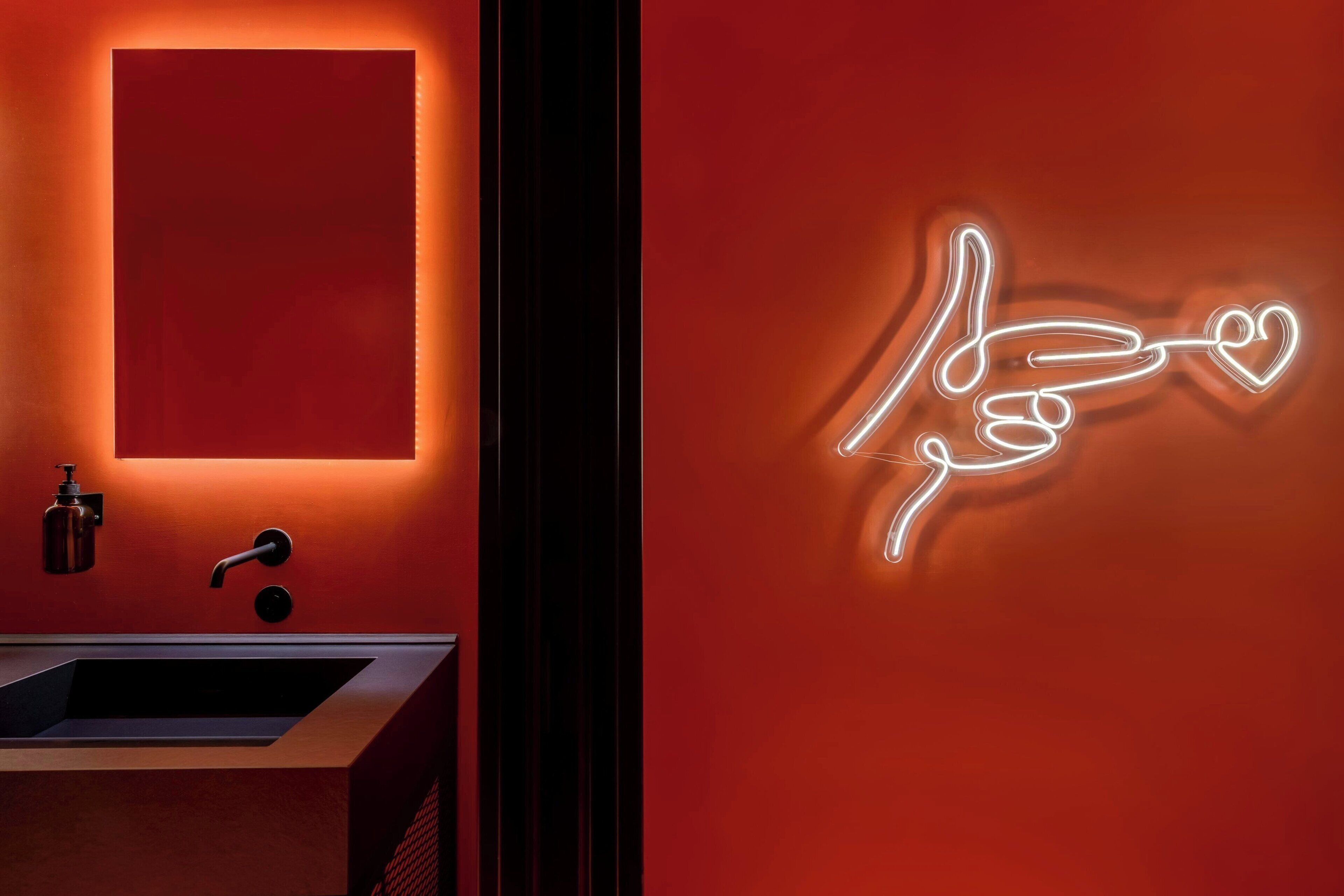 Ein modernes Badezimmer mit einer Neonreklame, einem Waschbecken und einem Spiegel.