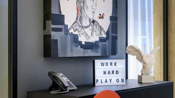 A modern interior with a large abstract painting, a motivational sign, a sculpture, and a telephone on a black console.