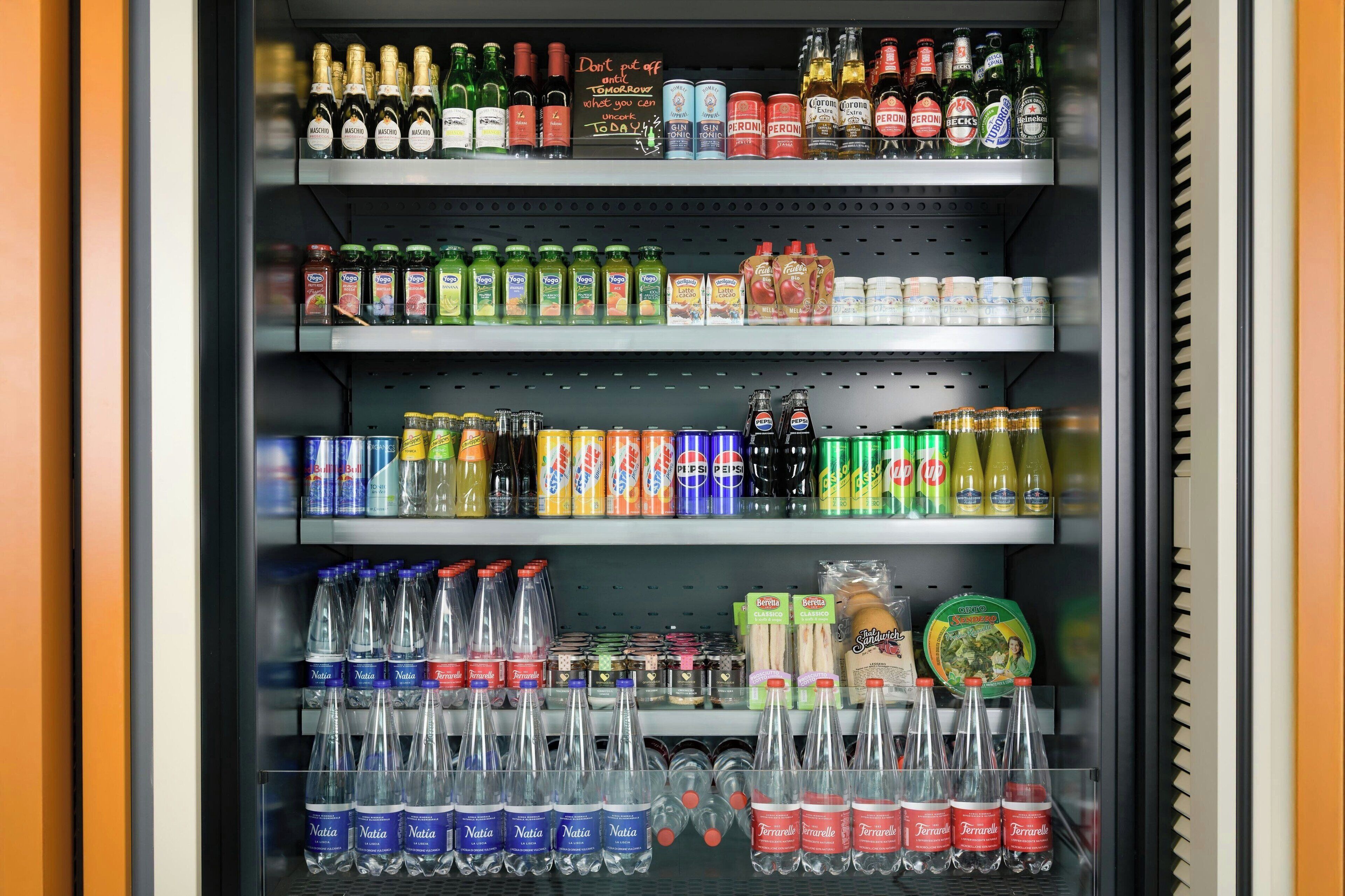 A beverage refrigerator stocked with various drinks including bottled water, sodas, and alcoholic beverages.