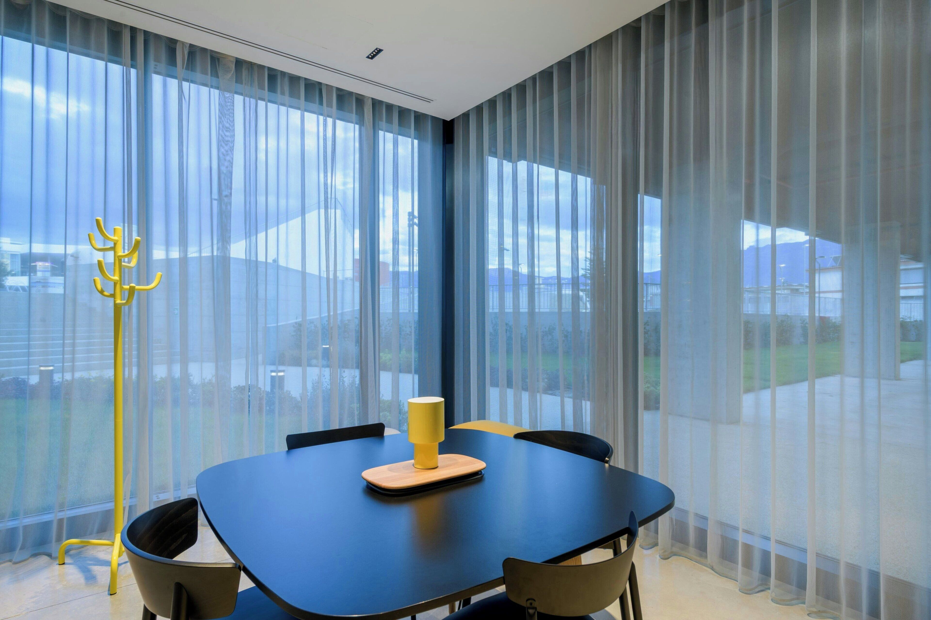 Un comedor moderno con una mesa, sillas y una lámpara amarilla.