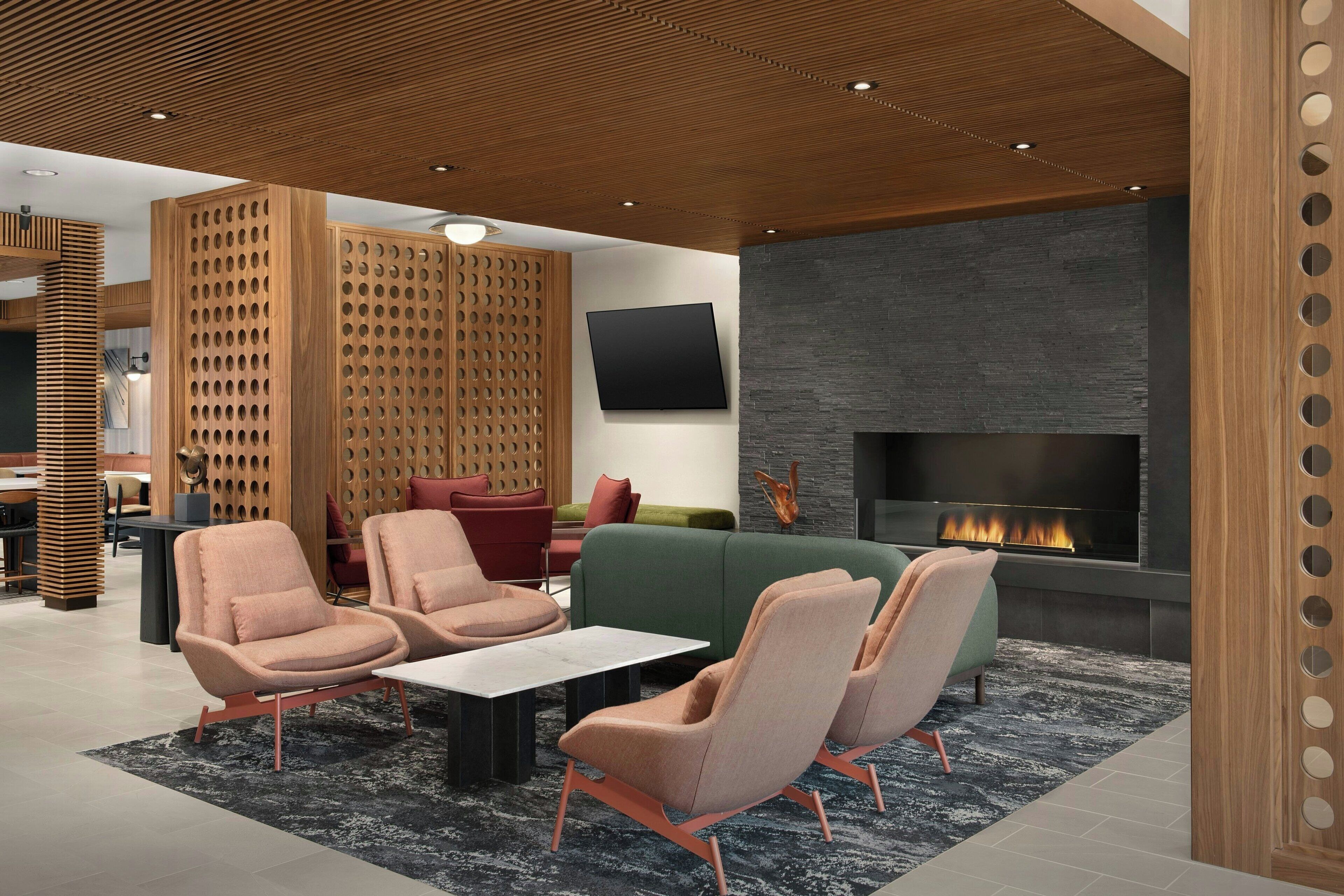 Un salon moderne doté d’une cheminée, de sièges confortables et d’une cloison en bois.