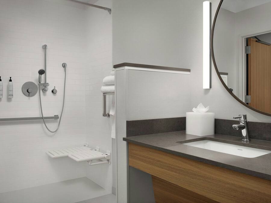 A modern bathroom with a shower, a sink, and a mirror.
