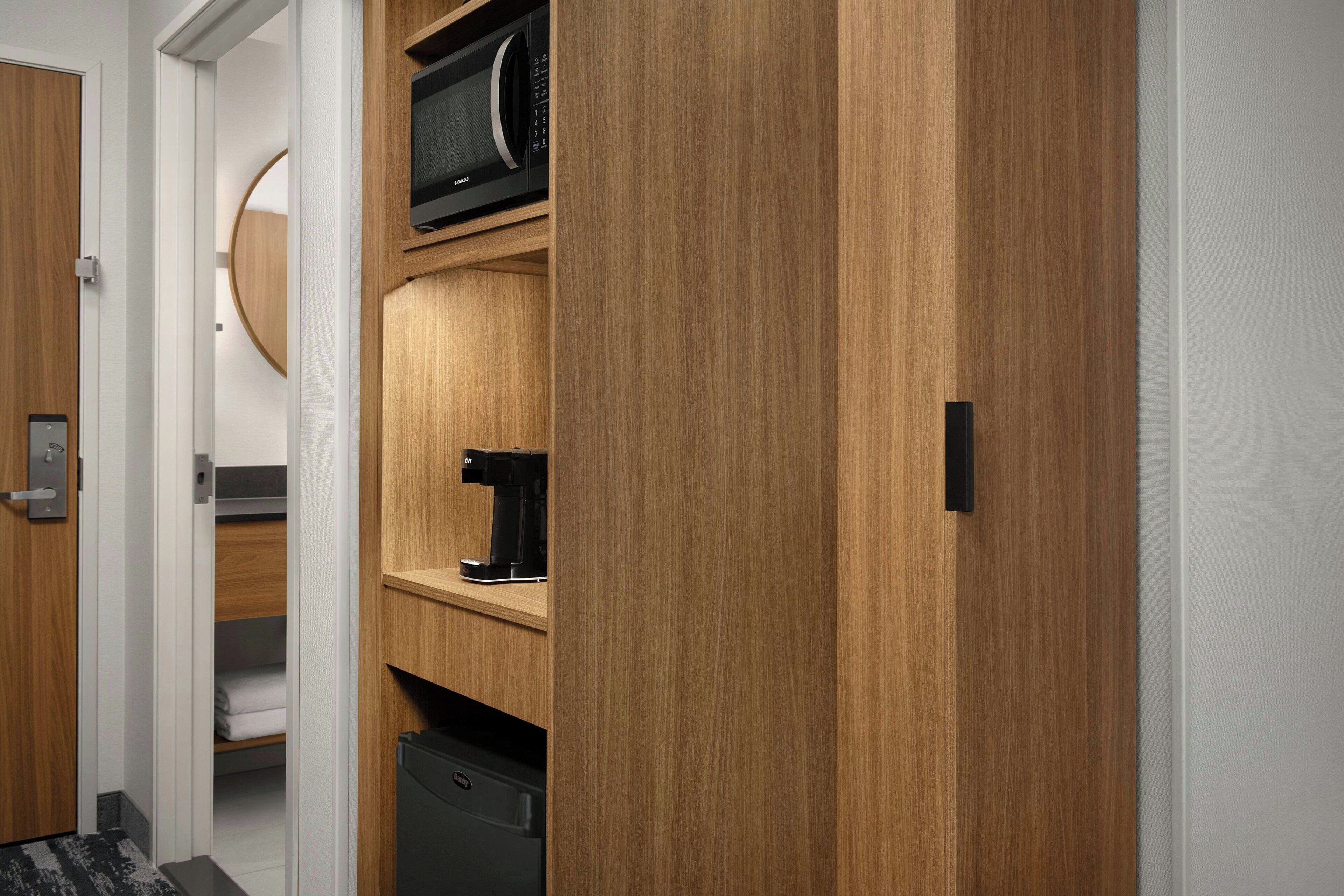 A modern kitchen with wooden cabinetry, a microwave, a coffee maker, and a dishwasher.