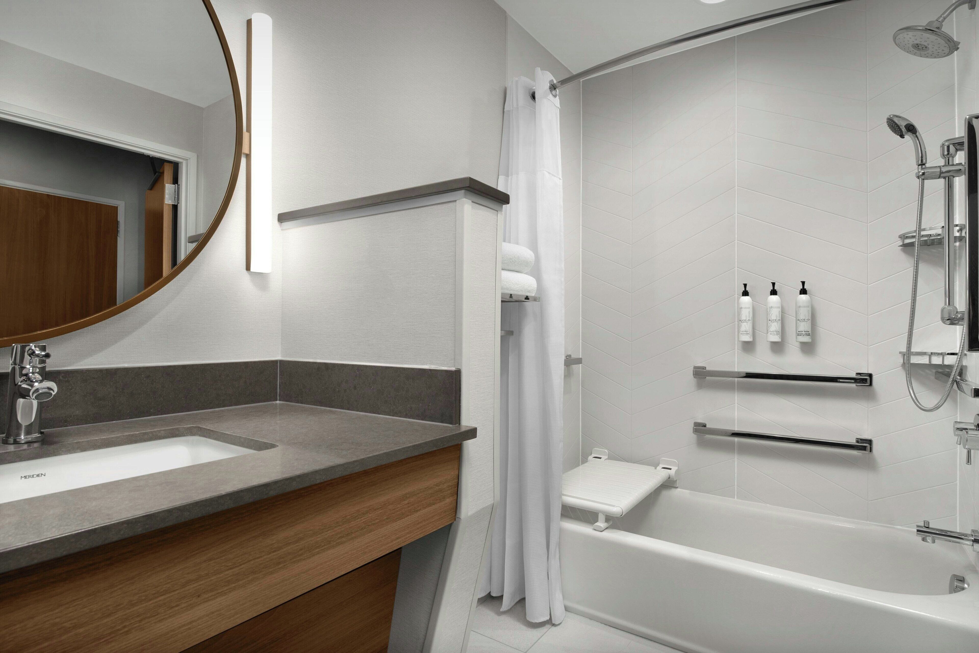 A modern bathroom with a sink, mirror, shower, and toilet.