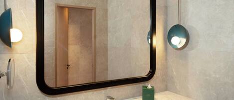 Un baño moderno con un espejo grande, encimera de mármol y estantes empotrados.