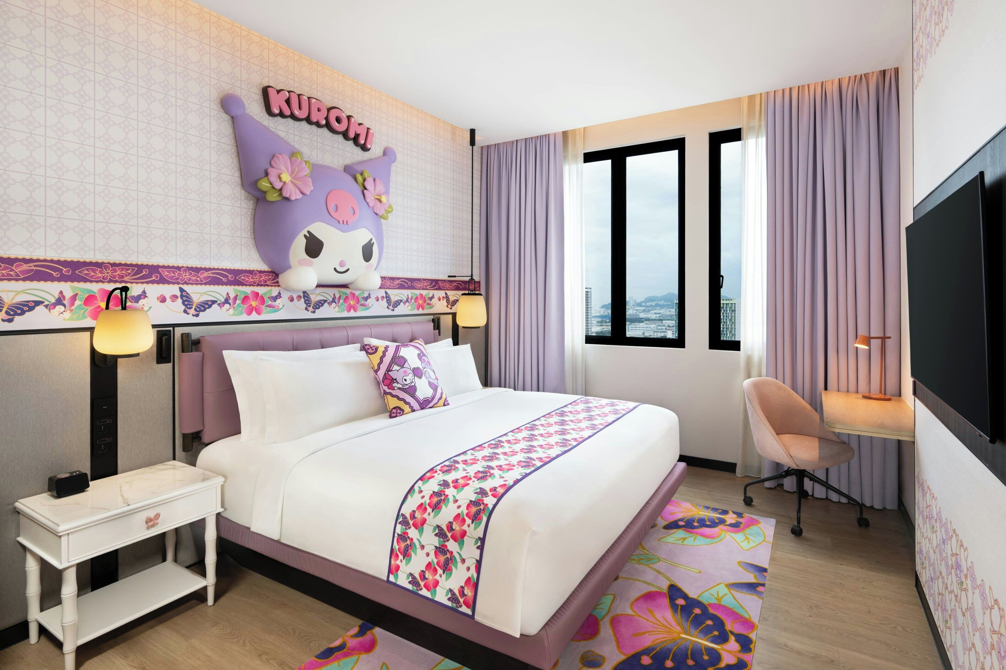 A hotel room with a bed, a desk, a chair, a TV, and a city view through the windows.