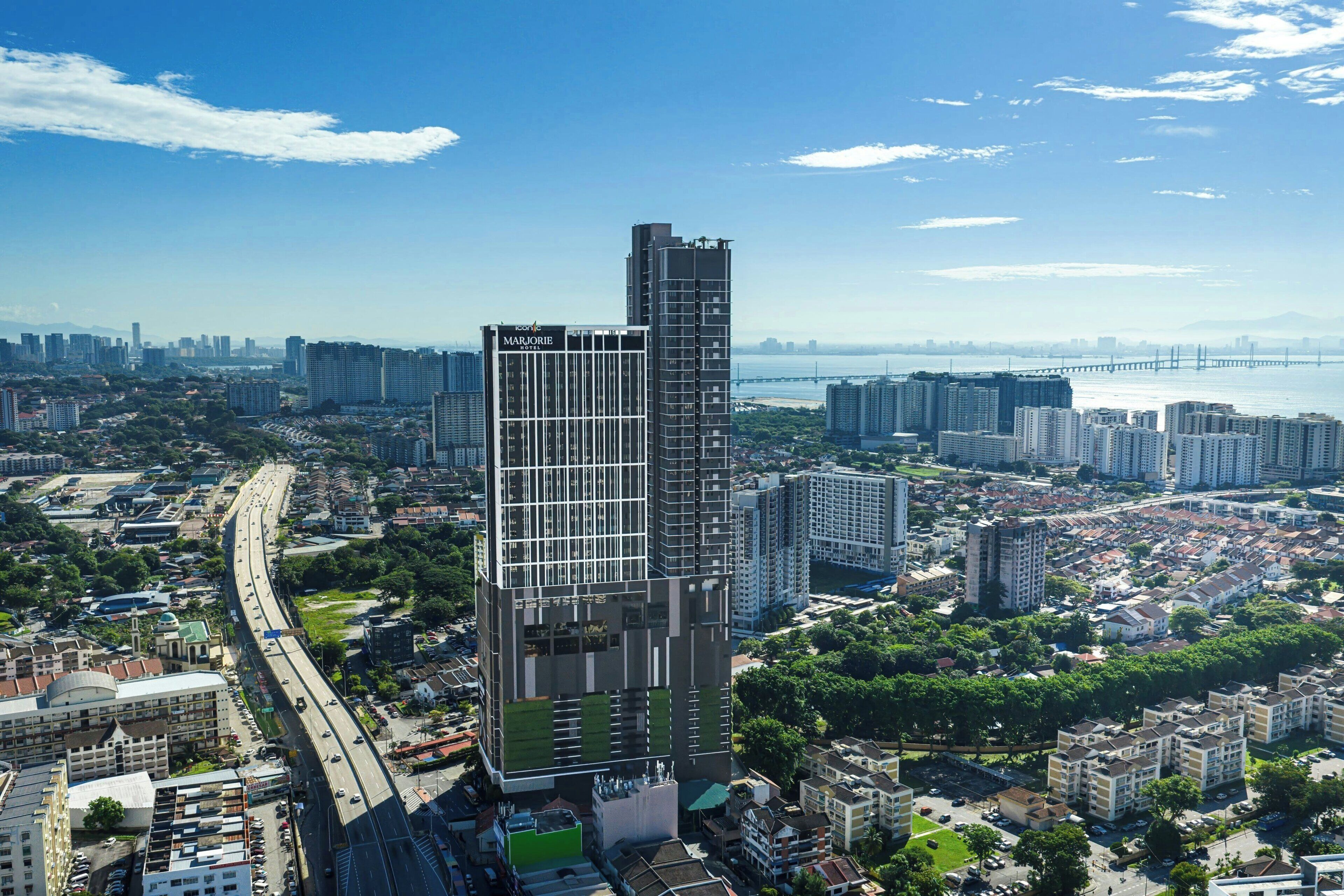 Un immeuble de grande hauteur à l’architecture moderne, entouré d’un paysage urbain et avec un pont en arrière-plan.