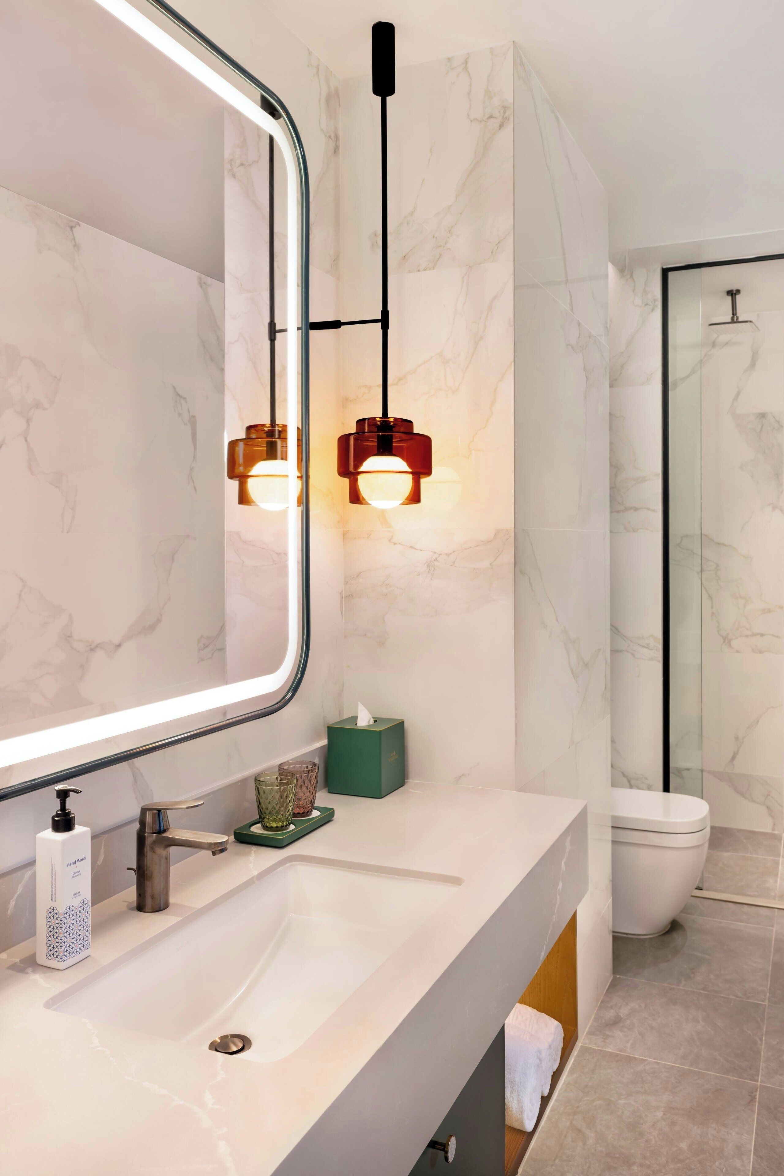 Une salle de bain moderne avec un grand miroir, un lavabo et des toilettes.