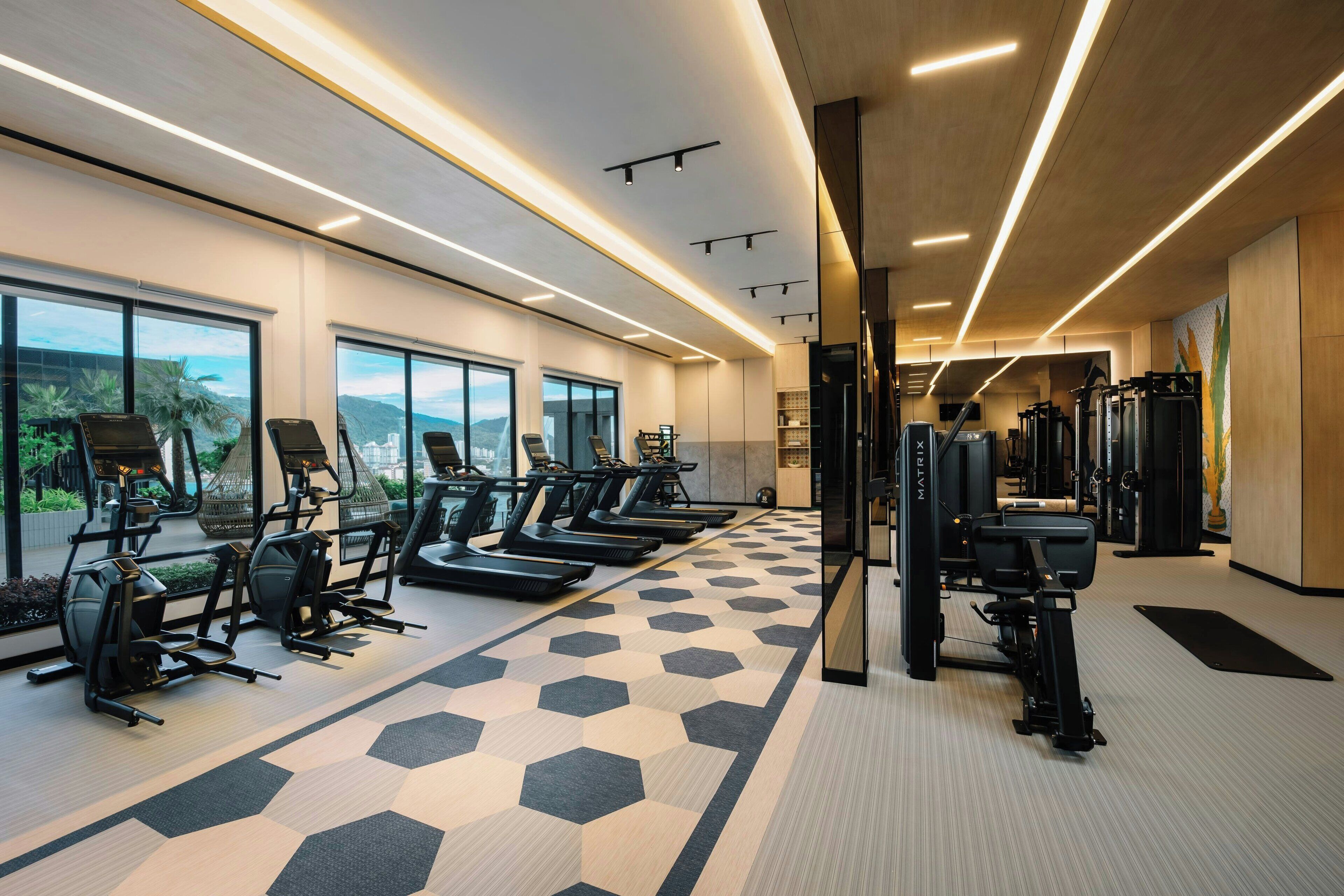 A modern gym with treadmills, stationary bikes, and weight machines.