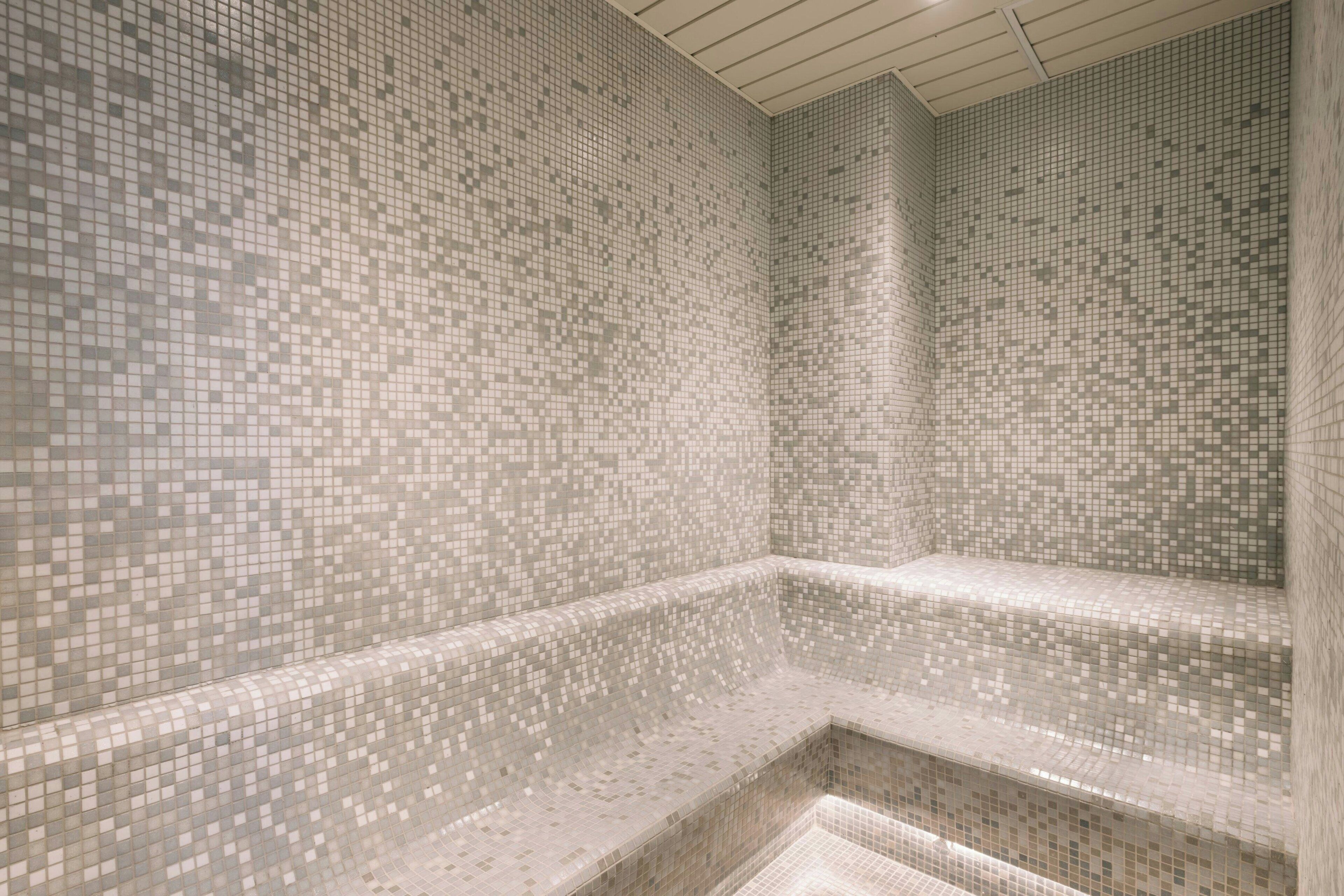A tiled bathroom with a mosaic pattern on the walls and floor.