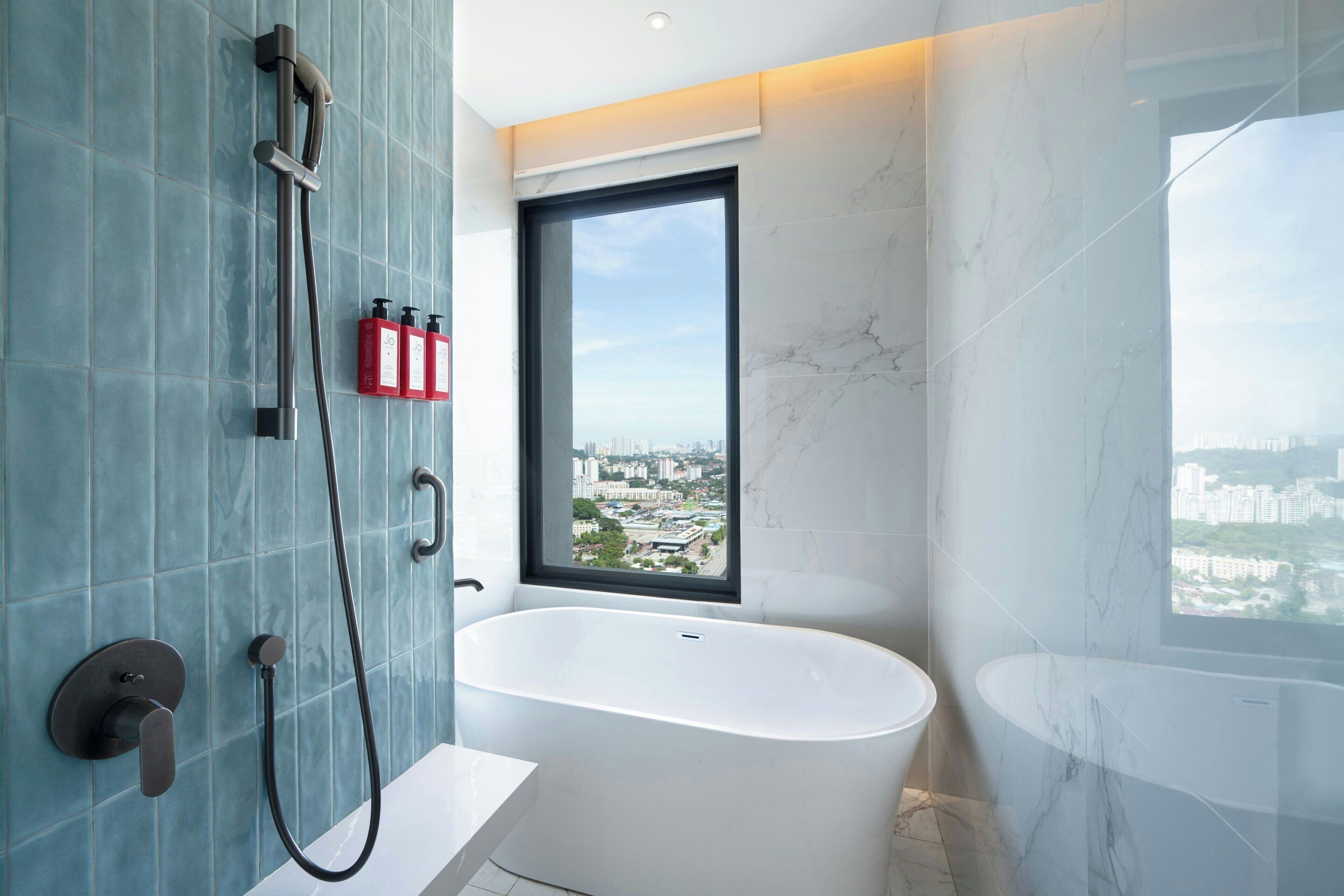 Un baño moderno con una bañera independiente, un ventanal con vistas a la ciudad y un sistema de ducha.