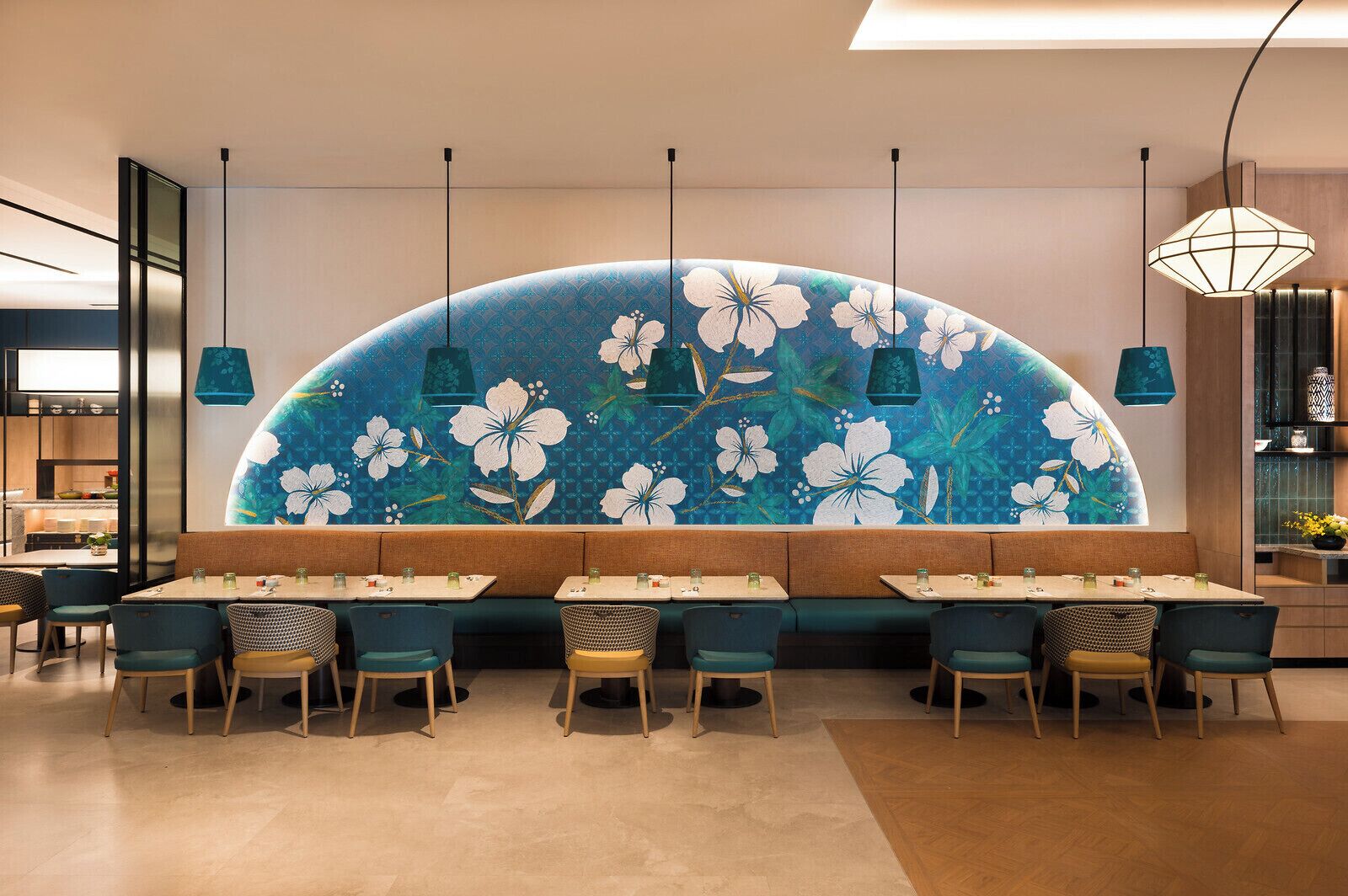A restaurant interior with a curved wall mural, multiple tables, and chairs.