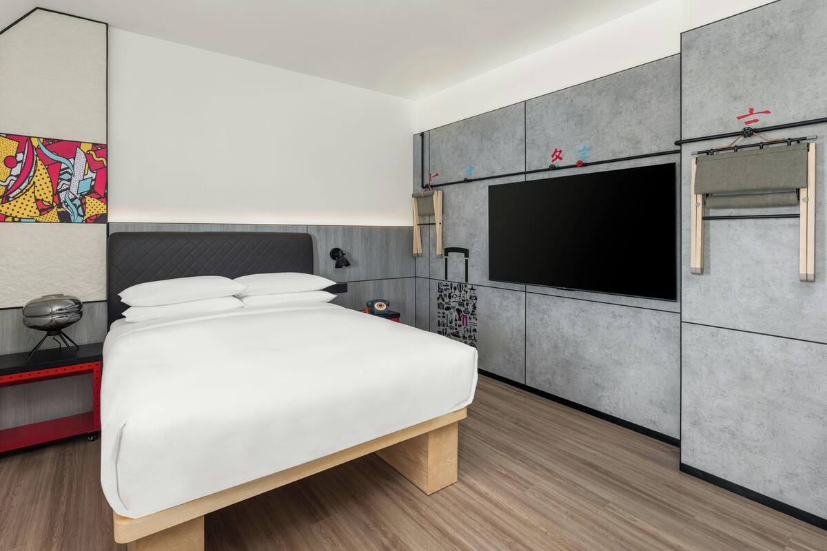A modern bedroom with a large bed, a TV, and a wardrobe.
