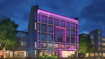 Un edificio moderno con un'insegna al neon, ampie vetrate e un ingresso ben illuminato.