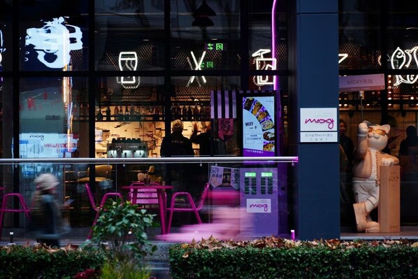 A storefront with neon signage, a vending machine, and a mascot figure. - Moxy Suzhou City Centre (Suzhou)
