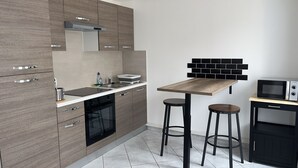 Ett modernt kök med en inbyggd ugn, en mikrovågsugn och en diskho. Det finns två barstolar och ett litet bord.