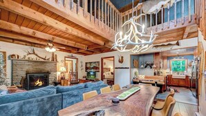 Amplia sala de estar con un gran comedor de madera, sofás azules y una chimenea.