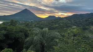 Un paysage montagneux caractérisé par un sommet imposant, une végétation luxuriante et des bâtiments dispersés.