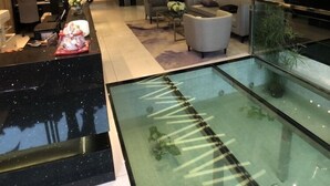 Un hall d’entrée moderne comprenant un comptoir d’accueil, un espace salon et une rambarde en verre donnant sur un niveau inférieur.