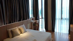 Une chambre d’hôtel avec un grand lit, un bureau et une vue par la fenêtre.