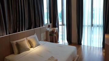 A hotel room with a large bed, a desk, and a view through the window.