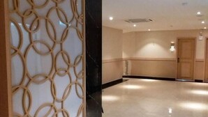 Un hall spacieux et bien éclairé, agrémenté d’un panneau décoratif en bois sur le côté gauche et d’un sol en marbre poli.