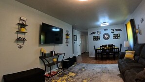A living room with a flat-screen TV, a ceiling fan, and a dining area with a table and chairs. - Cute 3 bedroom, 1 bath home less than 5 minutes from downtown. (Hot Springs)