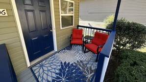 A porch with a dark blue door, two red chairs, and a patterned rug. - Cute 3 bedroom, 1 bath home less than 5 minutes from downtown. (Hot Springs)